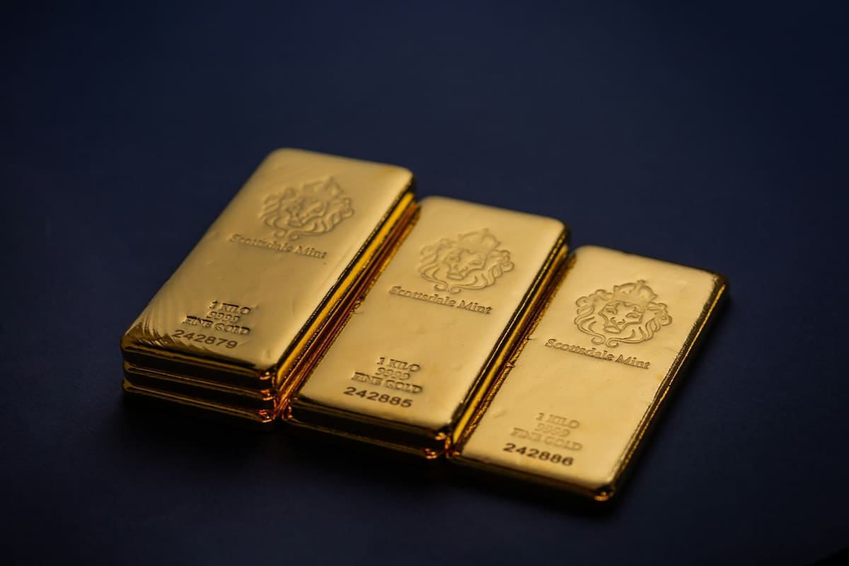 Pequeños lingotes y monedas de oro junto a una balanza digital